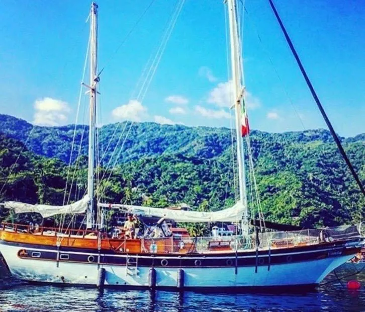 Slide: The Image of 1975 Formosa 51 sailboat anchored near lush green mountains under a clear blue sky. - 26