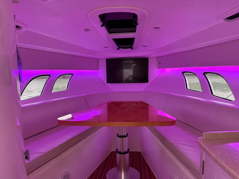Slide: The Image of 2013 Intrepid 400 Cuddy interior with purple lighting and a central wooden table. - 46