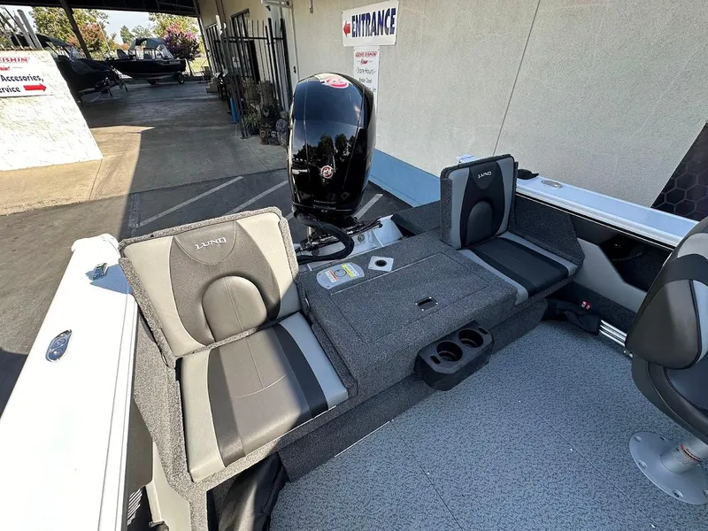 Slide: The Image of 2025 Lund 1875 Crossover XS boat interior with seating and motor, displayed outdoors. - 16