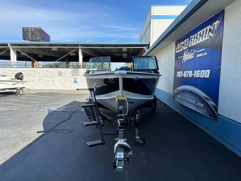 Slide: The Image of 2025 Lund 1875 Crossover XS boat on trailer at dealership, sunny day. - 2