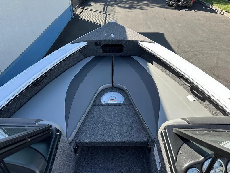 Slide: The Image of 2025 Lund 1875 Crossover XS boat interior with gray seating and carpeted flooring. - 26