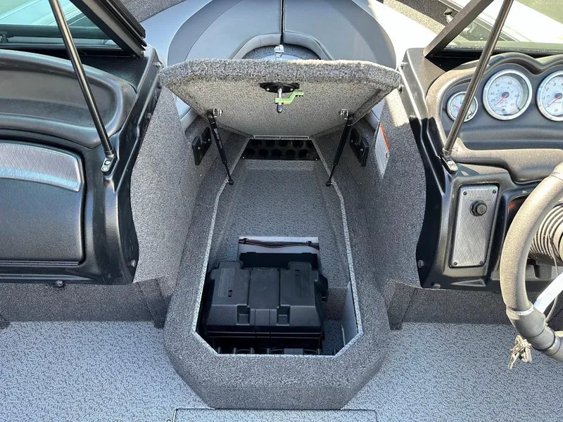 Slide: The Image of 2025 Lund 1875 Crossover XS boat interior with open storage compartment and dashboard view. - 28