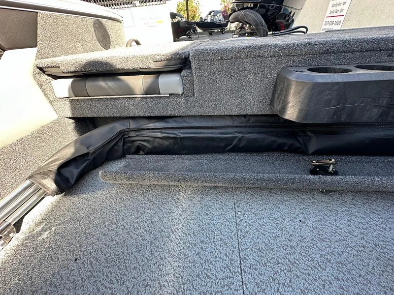 Slide: The Image of 2025 Lund 1875 Crossover XS boat interior with storage compartments and cup holders. - 32