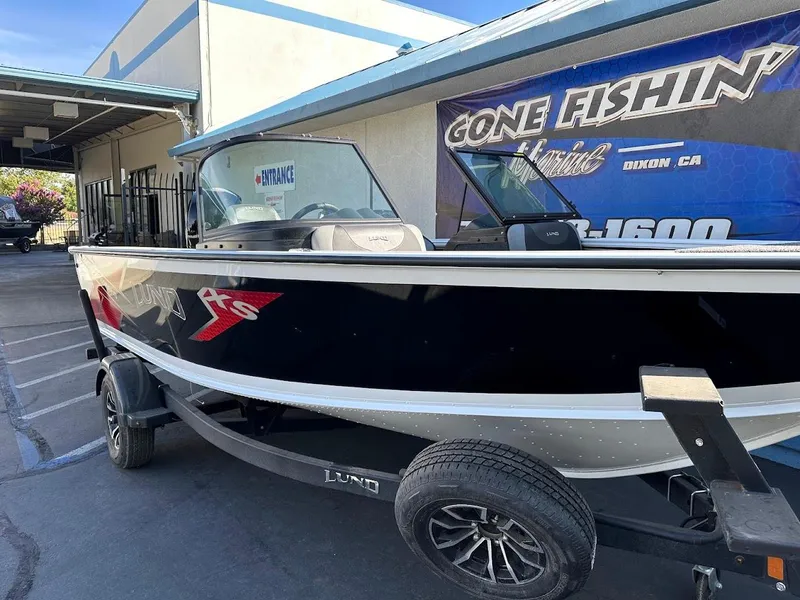 Slide: The Image of 2025 Lund 1875 Crossover XS boat on trailer at dealership entrance. - 5