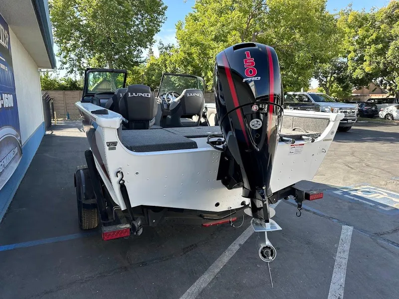 Slide: The Image of 2025 Lund 1875 Crossover XS boat with 150 HP engine, parked outdoors. - 9