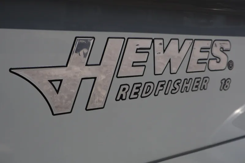 Slide: The Image of 2025 Hewes Redfisher 18 boat interior with steering wheel and motor, displayed at dealership. - 8