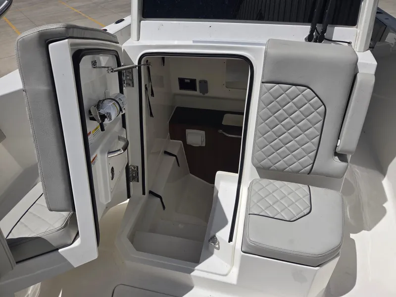 Slide: The Image of 2025 Pursuit S 288 Sport boat interior with open cabin door and cushioned seating. - 22