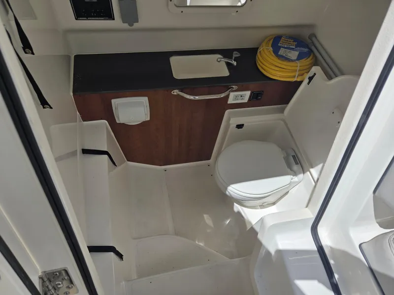 Slide: The Image of 2025 Pursuit S 288 Sport boat interior with toilet, sink, and storage area. - 23