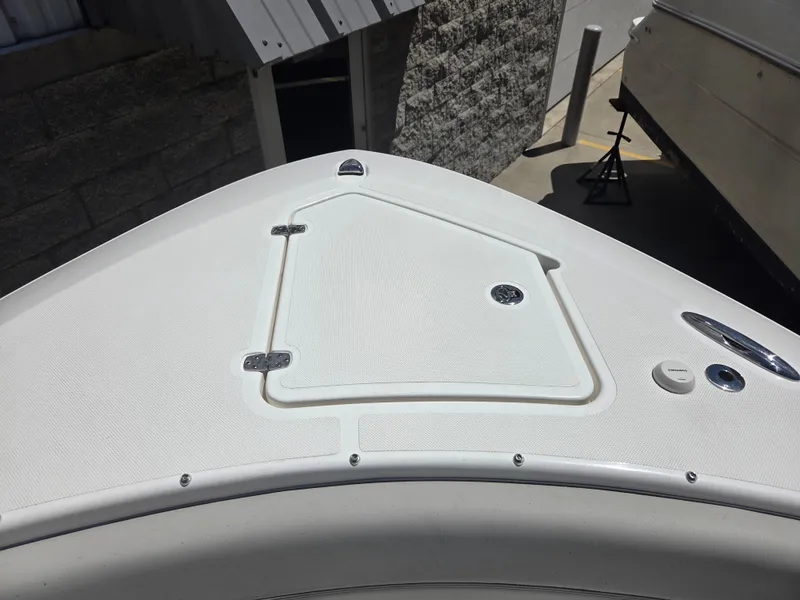 Slide: The Image of 2025 Pursuit S 288 Sport boat deck with storage hatch, docked near a stone wall. - 31