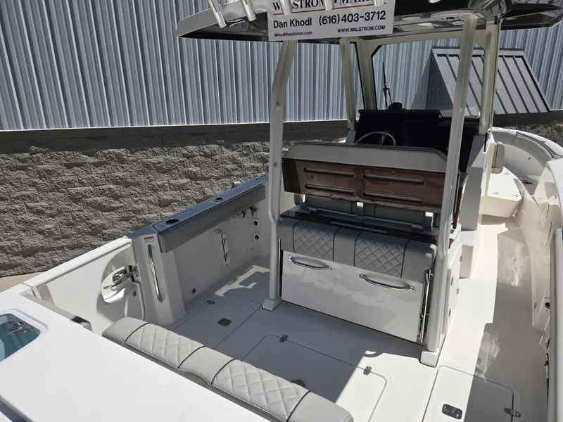 Slide: The Image of 2025 Pursuit S 288 Sport boat interior with seating and storage, docked near a corrugated wall. - 9