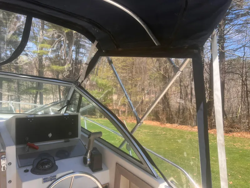 Slide: The Image of 1992 Grady-White 22 Seafarer boat interior with steering wheel and canopy, surrounded by trees. - 15