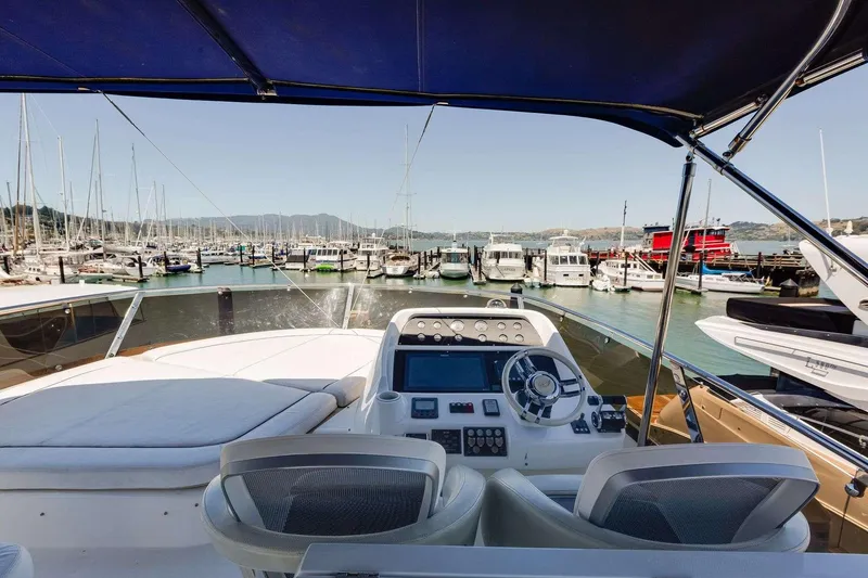 Slide: The Image of 2009 Sunseeker Manhattan 70 yacht helm with marina view, featuring modern controls and seating. - 12