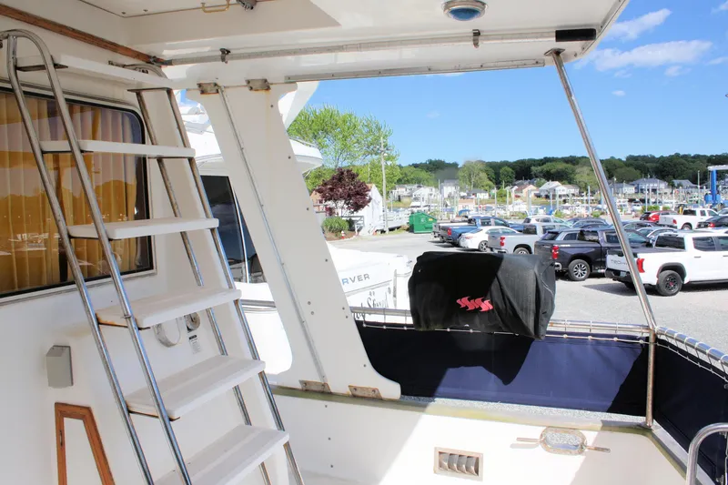 Slide: The Image of Island Gypsy 32 yacht deck with ladder, marina view, parked cars, and clear blue sky. - 13
