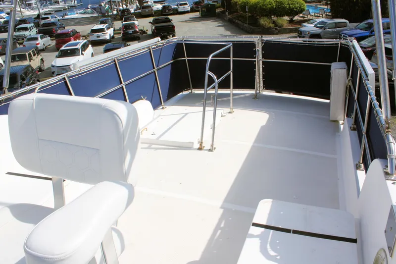 Slide: The Image of Flybridge of 2000 Island Gypsy 32 yacht with seating and railing, docked near parked cars. - 20