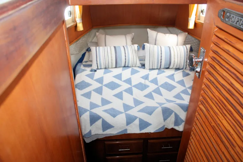 Slide: The Image of Cozy cabin interior of 2000 Island Gypsy 32 with geometric bedding and decorative pillows. - 26