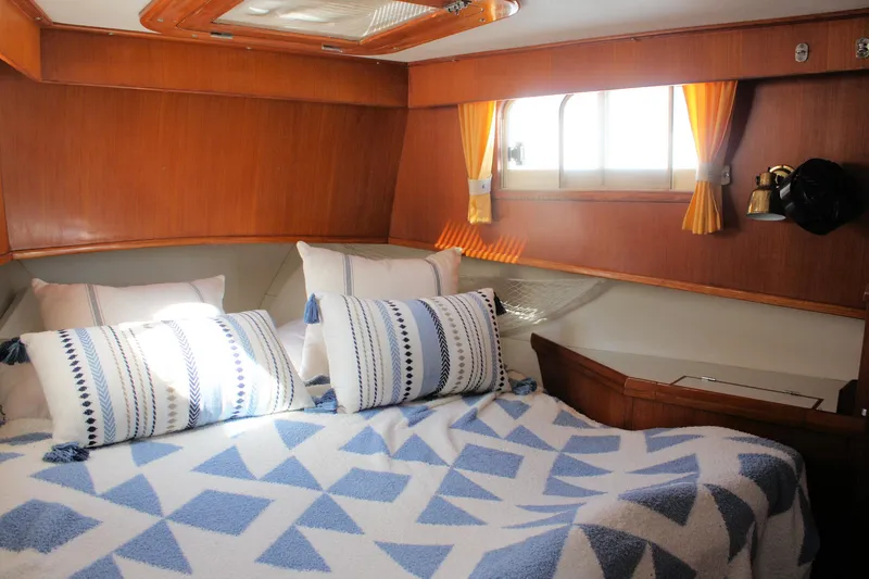 Slide: The Image of Cozy cabin interior of 2000 Island Gypsy 32 with patterned bedding and wooden accents. - 28