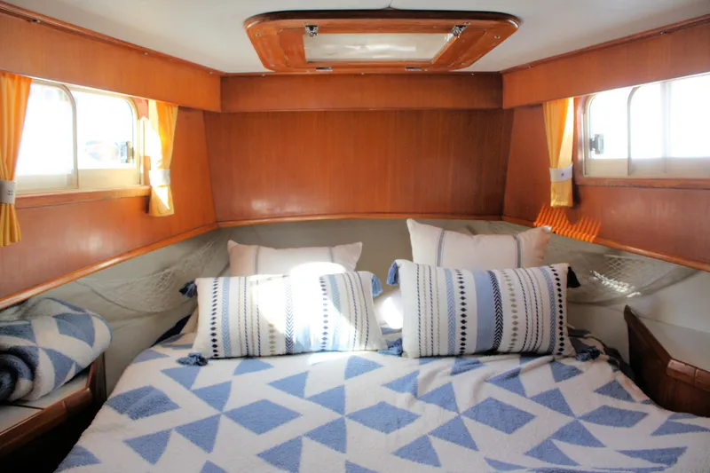 Slide: The Image of Cozy cabin interior of 2000 Island Gypsy 32 with patterned bedding and wooden accents. - 29