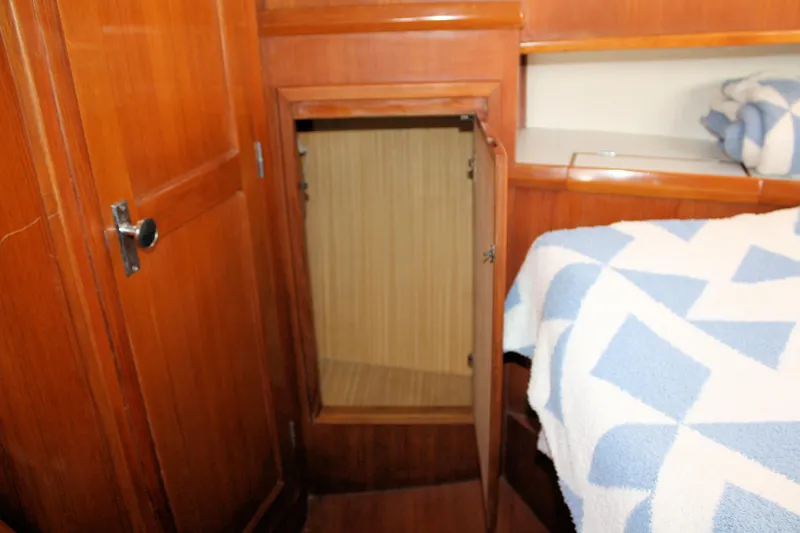 Slide: The Image of Interior of 2000 Island Gypsy 32 boat with open wooden cabinet and blue-patterned bedspread. - 31