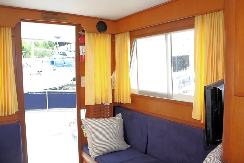 Slide: The Image of Interior of 2000 Island Gypsy 32 yacht with yellow curtains and blue seating. - 42
