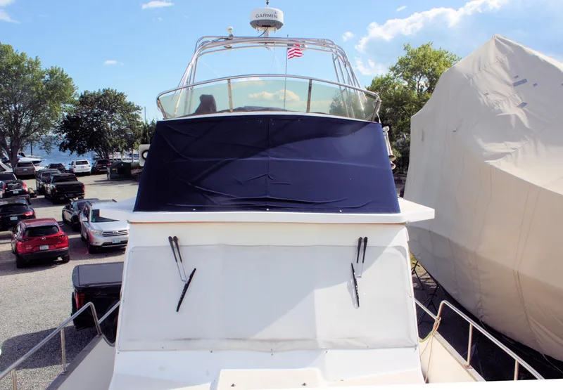 Slide: The Image of Island Gypsy 32 yacht, 2000 model, docked with cover, surrounded by parked cars and trees. - 6