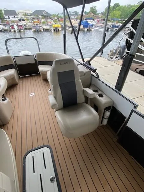 Slide: The Image of 2019 Coach Pontoons 230 RF Tritoon with spacious seating and elegant design at a marina. - 5