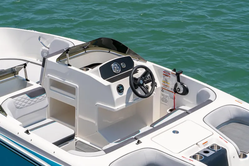 Slide: The Image of 2024 Bayliner M17 boat interior with steering wheel and seating, on calm water. - 11