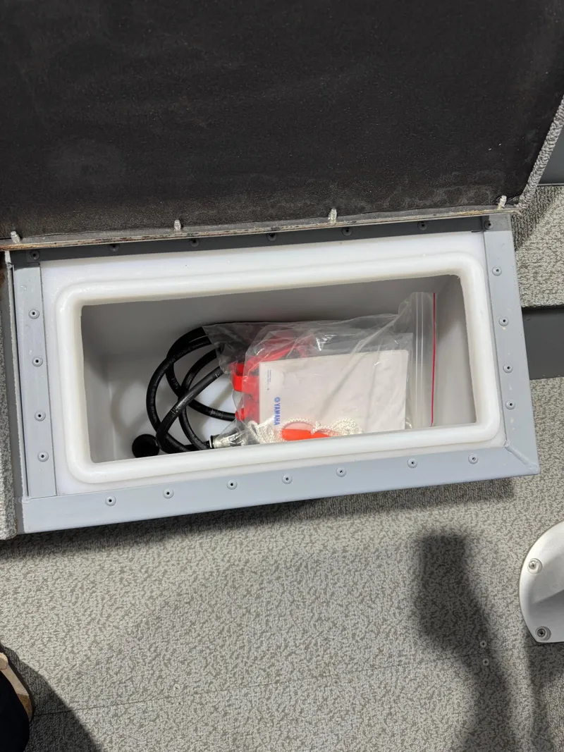 Slide: The Image of Open storage compartment in 2024 G3 V150T Guide boat, containing cables and a plastic bag. - 9