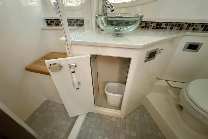Slide: The Image of 2025 Sea Ray Sundancer 370 bathroom with glass sink, toilet, and storage cabinet. - 24