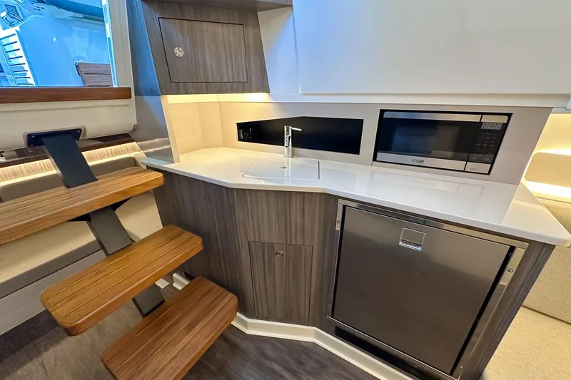 Slide: The Image of 2025 Sea Ray Sundancer 370 interior with modern kitchenette, featuring microwave and compact fridge. - 31