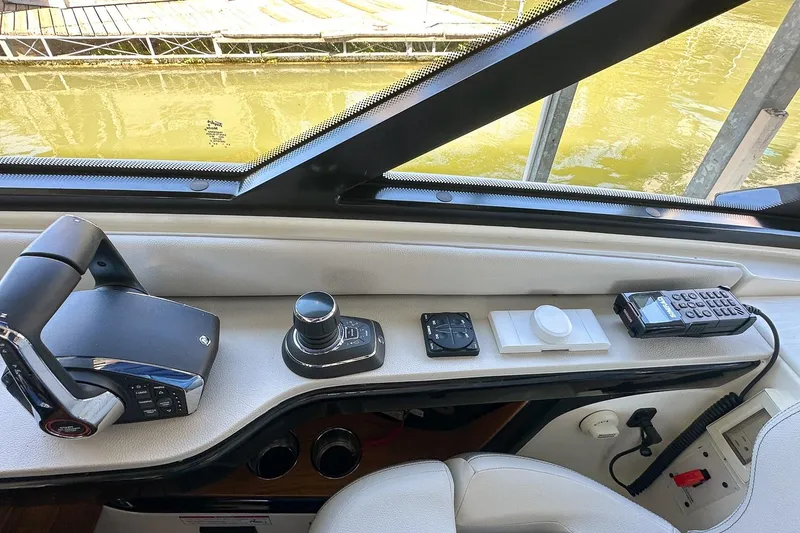 Slide: The Image of 2025 Sea Ray Sundancer 370 helm controls with joystick and radio, dockside view. - 38