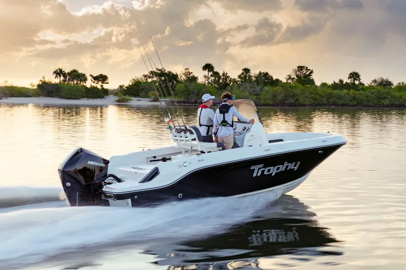Slide: The Image of 2023 Bayliner Trophy 20CC boat cruising on calm water at sunset. - 11