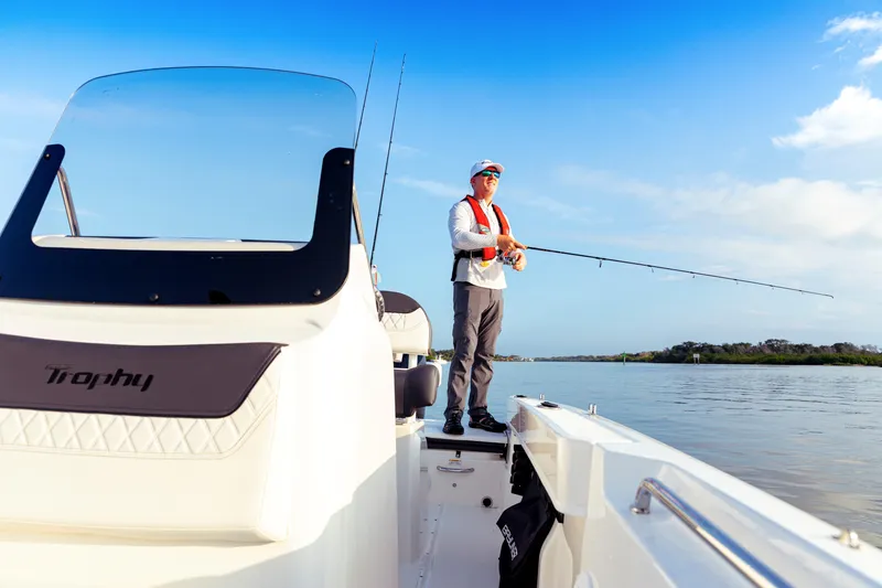 Slide: The Image of Man fishing on 2023 Bayliner Trophy 20CC boat under clear blue sky. - 17