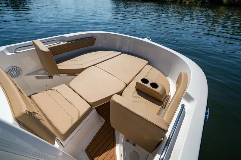 Slide: The Image of 2024 Bayliner Trophy 20CX boat interior with tan seating and cup holders on calm water. - 16