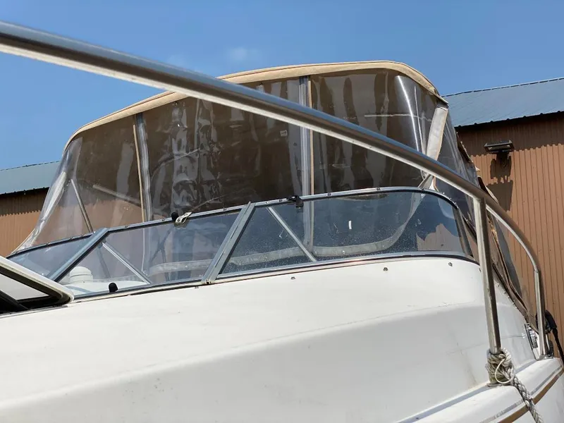 Slide: The Image of 2001 Larson 254 Cabrio boat with clear canopy and railing, under blue sky. - 3