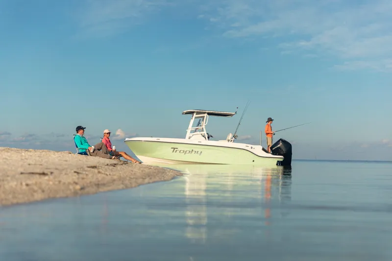 Slide: The Image of 2024 Bayliner Trophy 22CC boat near shore with people relaxing and fishing. - 1