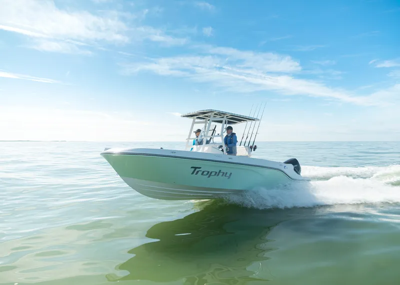 Slide: The Image of 2024 Bayliner Trophy 22CC boat cruising on calm water under a clear blue sky. - 2