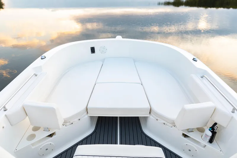 Slide: The Image of 2024 Bayliner Trophy 22CC boat interior with cushioned seating on calm water. - 25