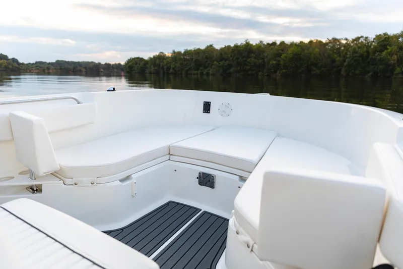 Slide: The Image of 2024 Bayliner Trophy 22CC boat interior with white seating on a calm lake. - 27