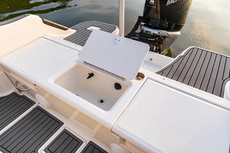Slide: The Image of 2024 Bayliner Trophy 22CC boat deck with open storage compartment and outboard motor. - 6