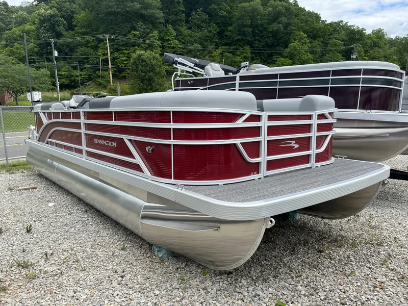 The Image of 2024 Bennington 22 SVSR-SPS pontoon boat with red and silver design, parked on gravel. - 1