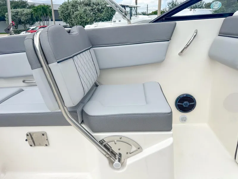 Slide: The Image of 2024 Bayliner DX2200 boat interior with gray cushioned seating and stainless steel handrail. - 16