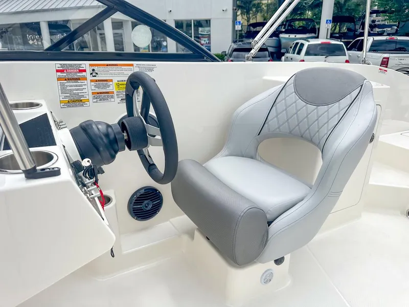 Slide: The Image of 2024 Bayliner DX2200 boat cockpit with steering wheel and cushioned seat. - 23