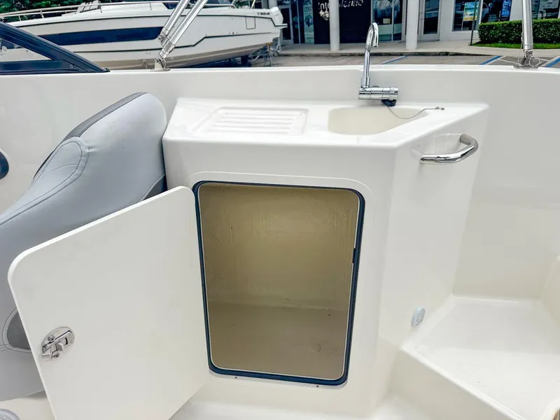 Slide: The Image of 2024 Bayliner DX2200 boat interior with open storage compartment and sink. - 26