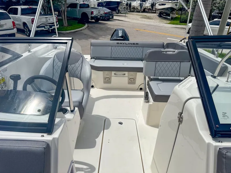 Slide: The Image of 2024 Bayliner DX2200 boat interior with seating and steering wheel, parked outdoors. - 29