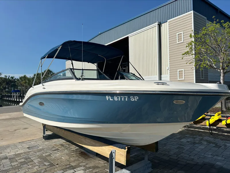 The Image of 2020 Sea Ray SPX 230 OB boat with blue hull, docked outdoors. - 0