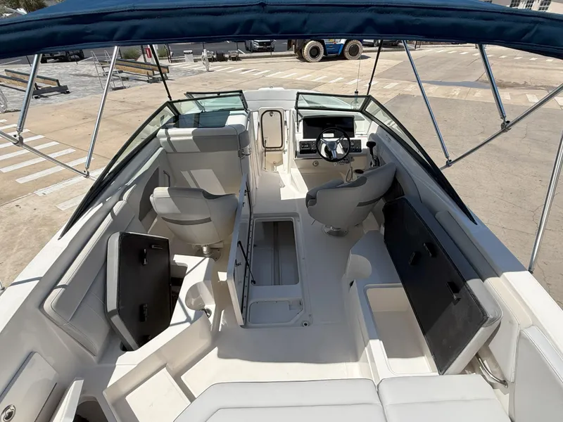 Slide: The Image of 2020 Sea Ray SPX 230 OB boat interior with seating and steering wheel, docked under canopy. - 16