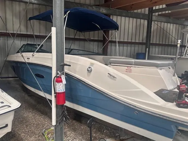 Slide: The Image of 2020 Sea Ray SPX 230 OB boat in storage with blue canopy. - 6
