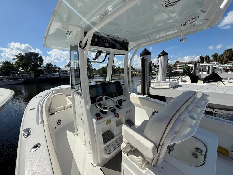 Slide: The Image of 2023 Sea Hunt Gamefish 25 boat interior with helm, seating, and marina view. - 13