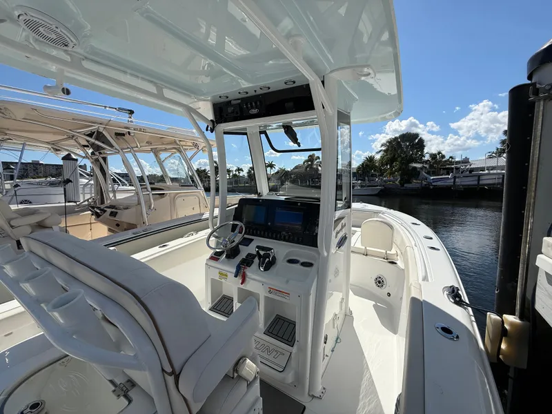 Slide: The Image of 2023 Sea Hunt Gamefish 25 boat interior with helm, docked under clear sky. - 14