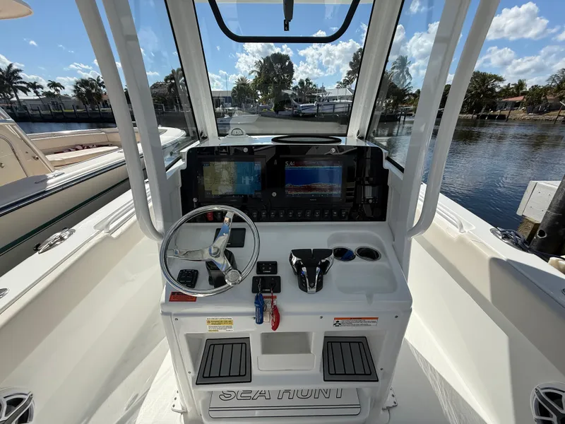 Slide: The Image of 2023 Sea Hunt Gamefish 25 boat console with steering wheel and navigation screens. - 15